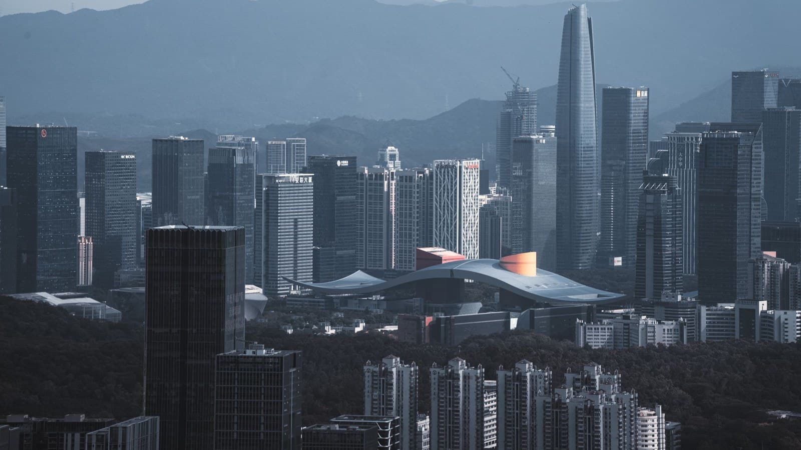 黄昏时的深圳天际线，密集的高楼一直延伸到城市背后的山脉。