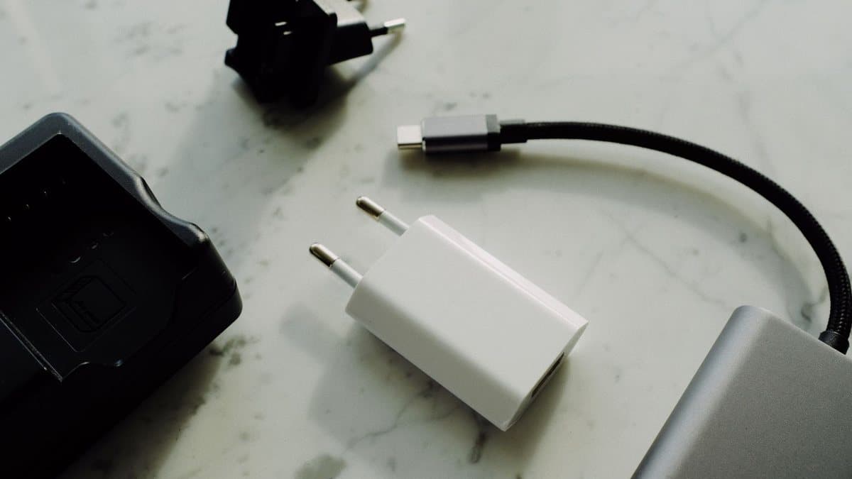 Various electronic charging accessories, including adapters, a cable, and a black device, are scattered on a light surface.