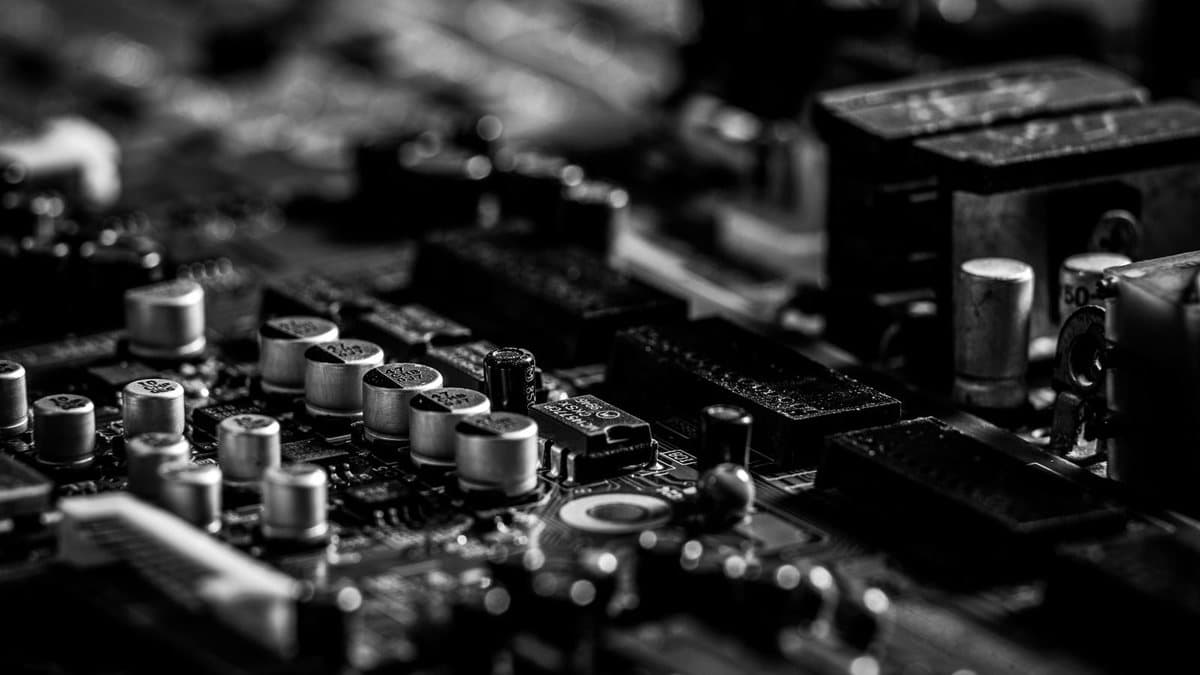 A detailed black and white close-up shows numerous capacitors and other electronic components densely packed on a circuit board.