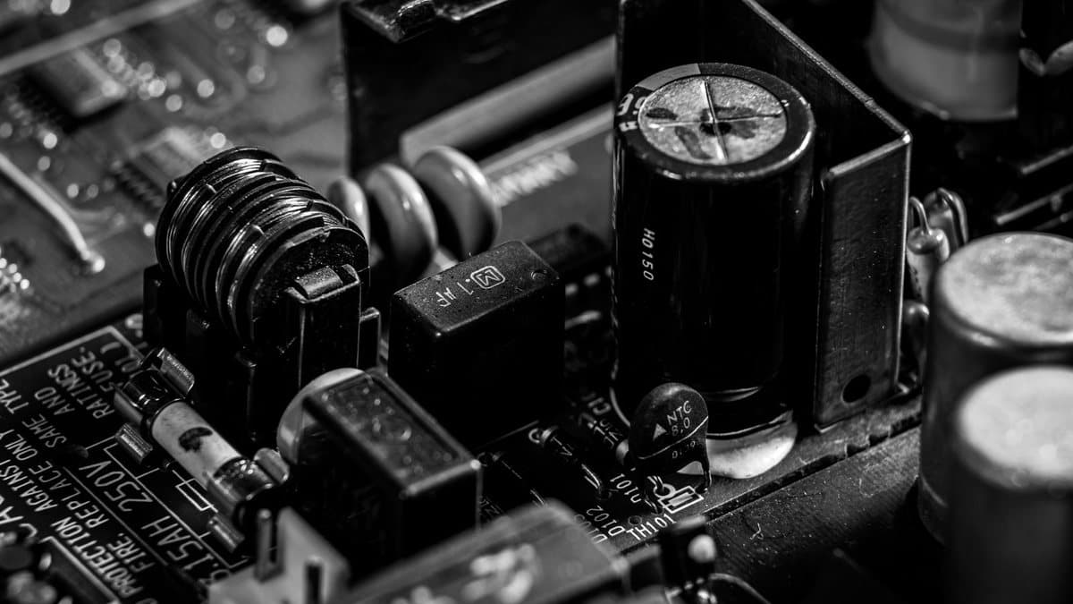 Close-up of electronic components: capacitors, an inductor, and a fuse, mounted on a dark circuit board.