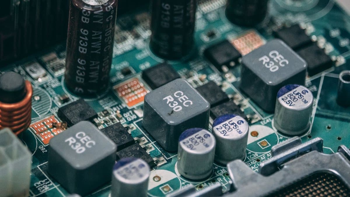 A detailed close-up reveals an intricate network of electronic components including capacitors and inductors on a green circuit board.