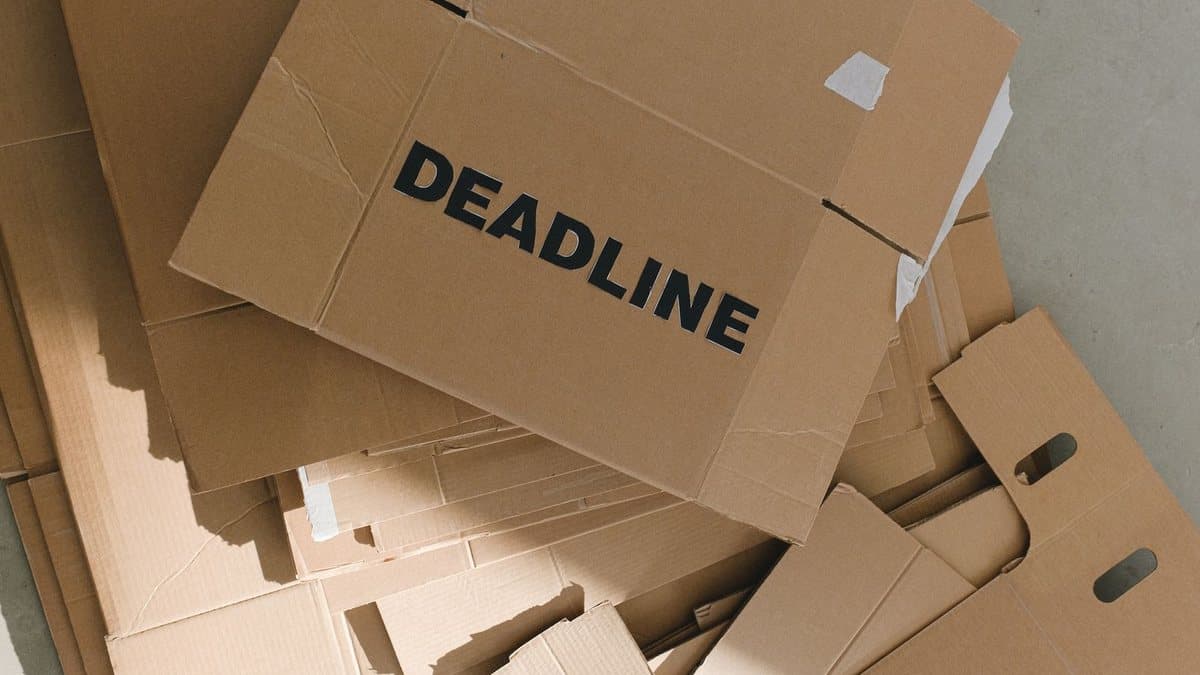 A pile of brown cardboard boxes with the word 'DEADLINE' printed on one, scattered on a concrete floor.