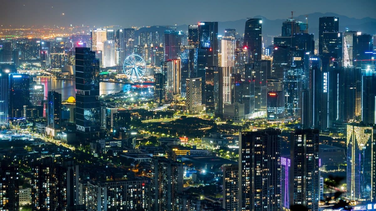夜幕下广阔的城市景观,展示着众多璀璨的摩天大楼、一座显眼的摩天轮和波光粼粼的水道。